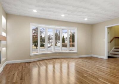 A Large, Open Living Room With Wooden Floors And A Fireplace.